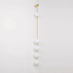 The Clérachic Stacked Globe Wall Sconce in brass, unlit, five opal globes on a plain white studio backdrop.