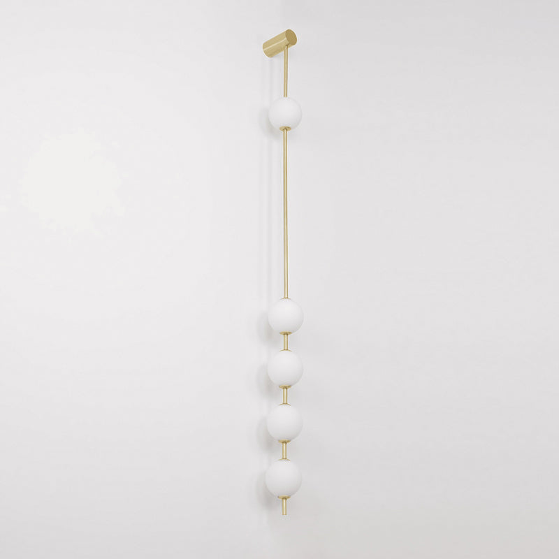 The Clérachic Stacked Globe Wall Sconce in brass, unlit, five opal globes on a plain white studio backdrop.