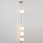 The Clérachic Stacked Globe Wall Sconce in brushed nickel, lit, four globes glowing warm against white.