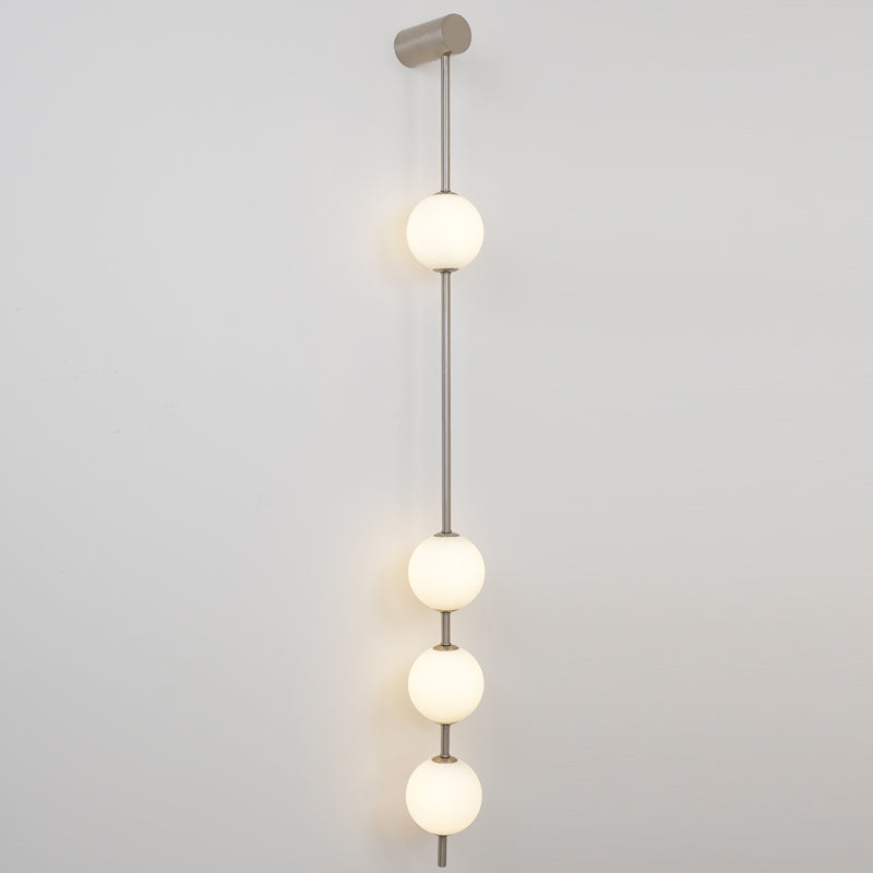 The Clérachic Stacked Globe Wall Sconce in brushed nickel, lit, four globes glowing warm against white.