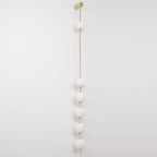 The Clérachic Stacked Globe Wall Sconce in brass, unlit, six opal globes stacked down a slim brass rod.