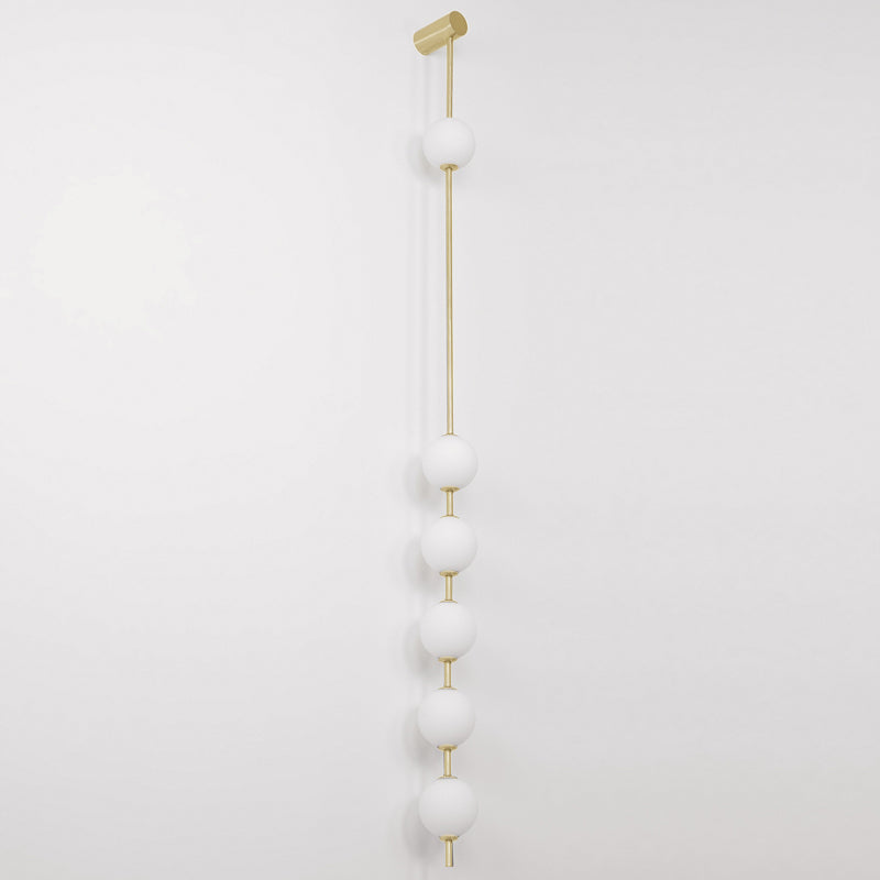 The Clérachic Stacked Globe Wall Sconce in brass, unlit, six opal globes stacked down a slim brass rod.