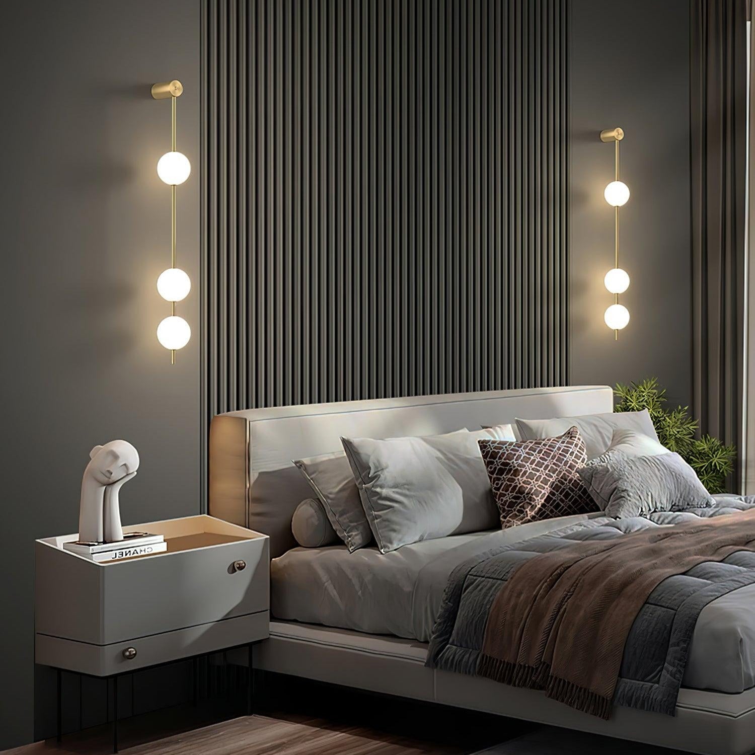 Two Clérachic Stacked Globe Wall Sconces in brass, lit, flanking a fluted headboard with three globes each.