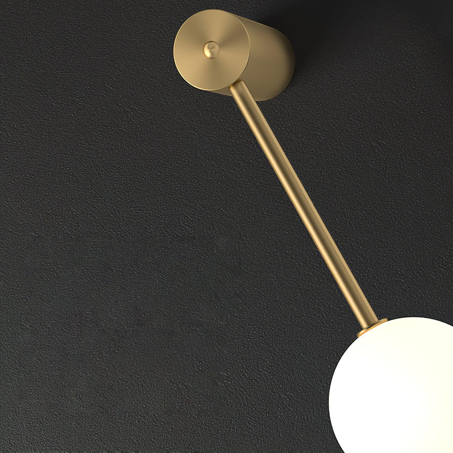 Detail of the Clérachic Stacked Globe Wall Sconce's brass wall mount and slim connecting rod on a dark backdrop.