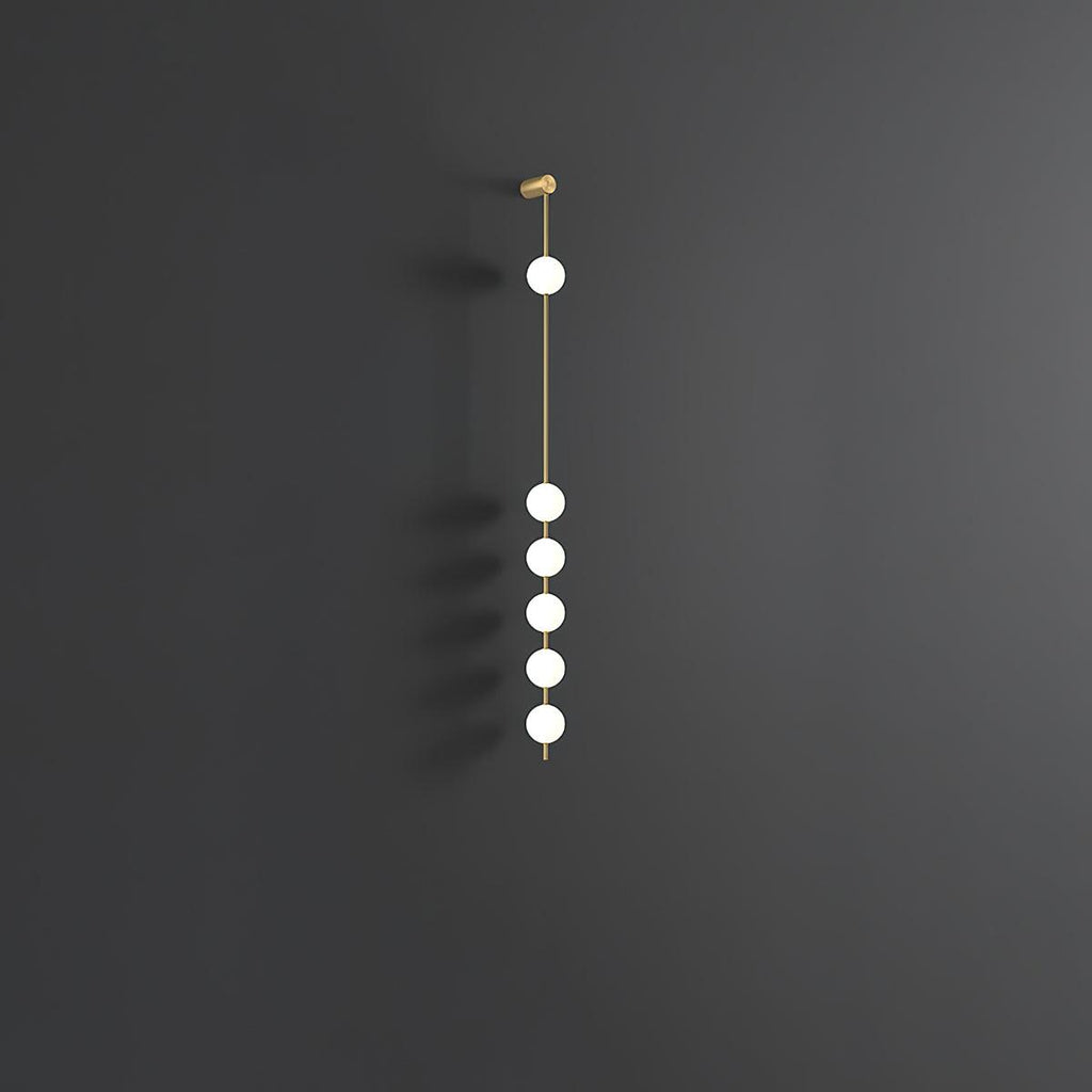 The Clérachic Stacked Globe Wall Sconce in brass, unlit, six globes against a dark grey studio backdrop.