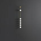 The Clérachic Stacked Globe Wall Sconce in brass, unlit, six globes against a dark grey studio backdrop.