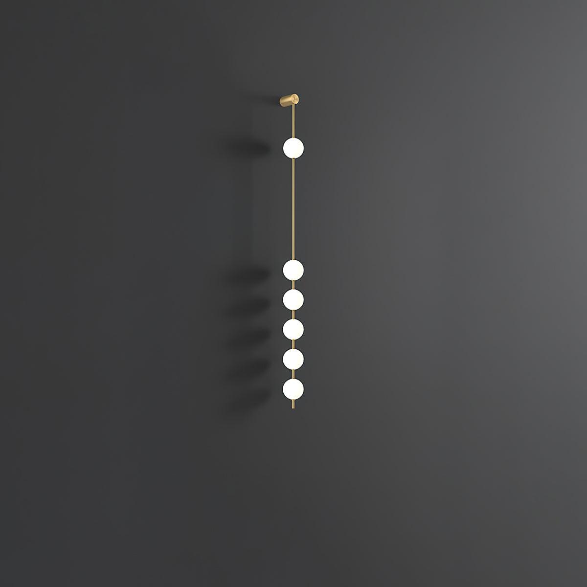 The Clérachic Stacked Globe Wall Sconce in brass, unlit, six globes against a dark grey studio backdrop.