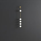 The Clérachic Stacked Globe Wall Sconce in brass, unlit, five globes against a dark grey studio backdrop.