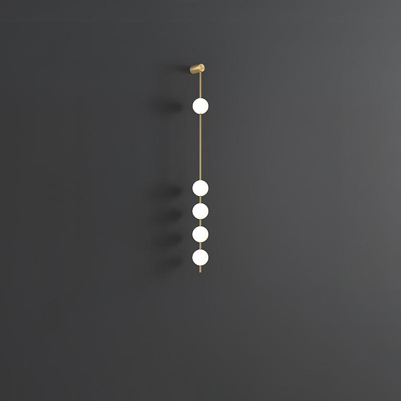 The Clérachic Stacked Globe Wall Sconce in brass, unlit, five globes against a dark grey studio backdrop.