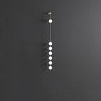 The Clérachic Stacked Globe Wall Sconce in brass, lit, six globes shown at an angle on a dark grey backdrop.