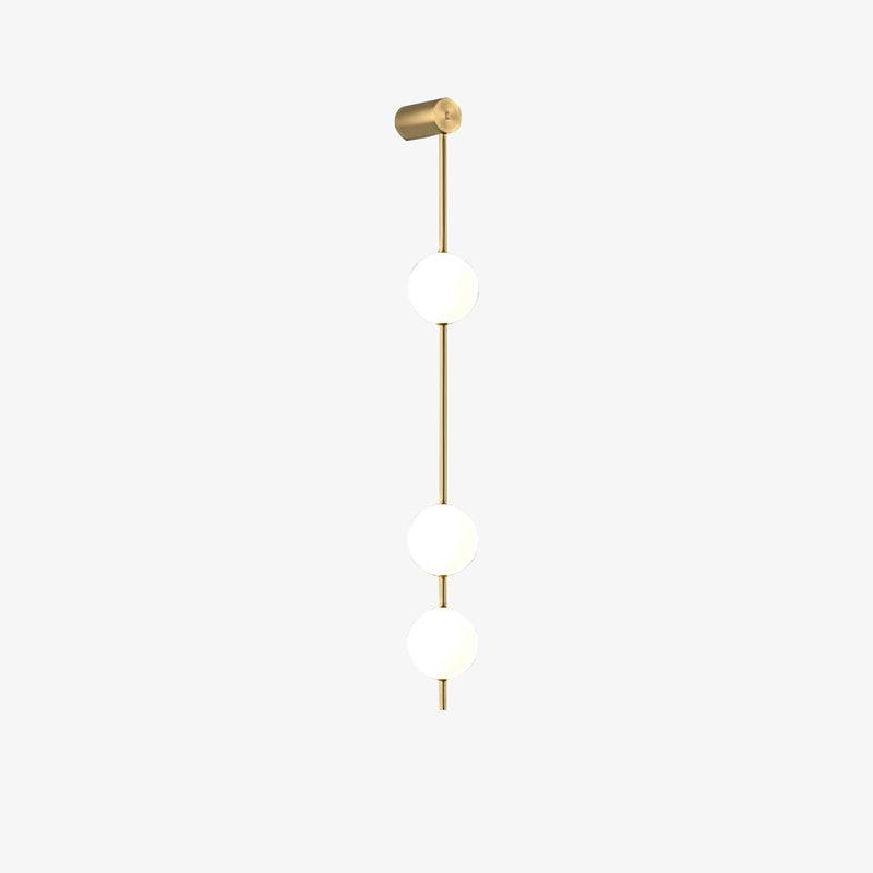 The Clérachic Stacked Globe Wall Sconce in brass, lit, three globes with the wall mount angled slightly.
