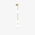 The Clérachic Stacked Globe Wall Sconce in brass, lit, three globes with the wall mount angled slightly.