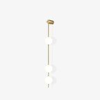The Clérachic Stacked Globe Wall Sconce in brass, lit, three globes photographed from a side angle.