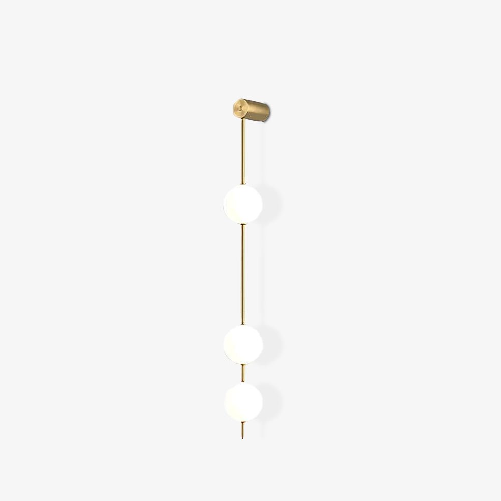 The Clérachic Stacked Globe Wall Sconce in brass, lit, three globes photographed from a side angle.