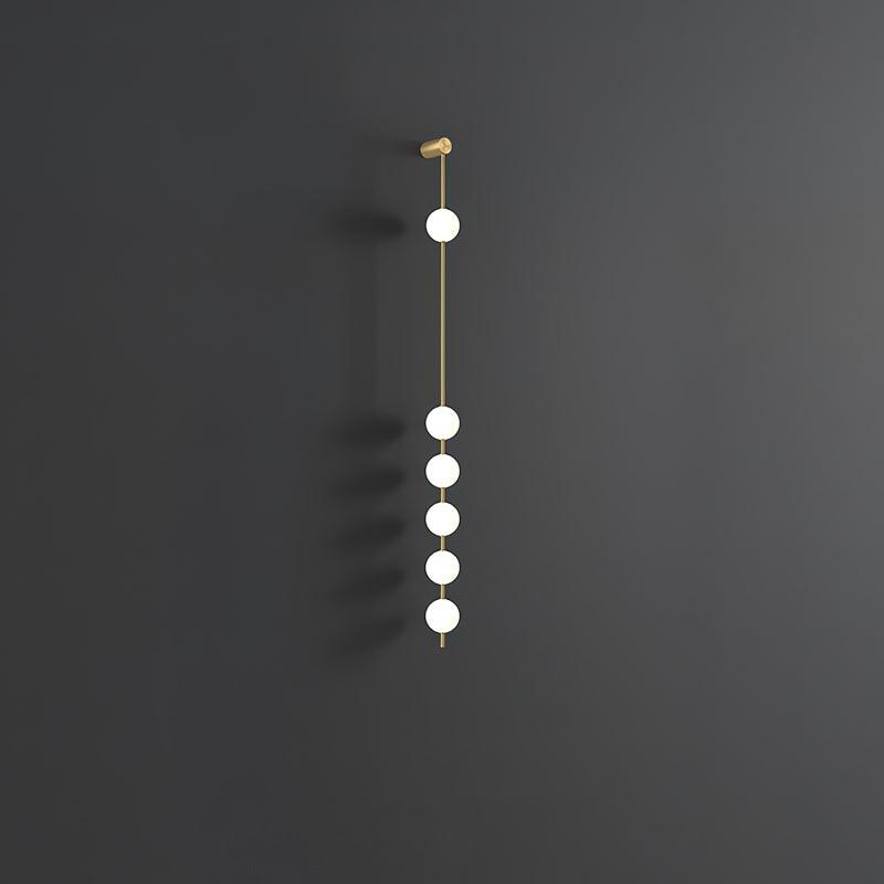 The Clérachic Stacked Globe Wall Sconce in brass, lit, six globes shown at an angle against dark grey.