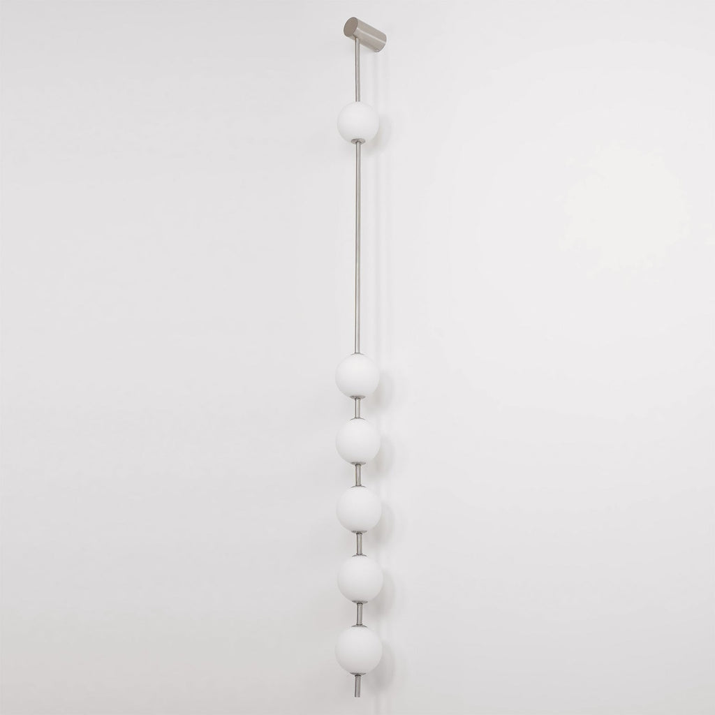 The Clérachic Stacked Globe Wall Sconce in brushed nickel, lit, six globes on a plain white backdrop.