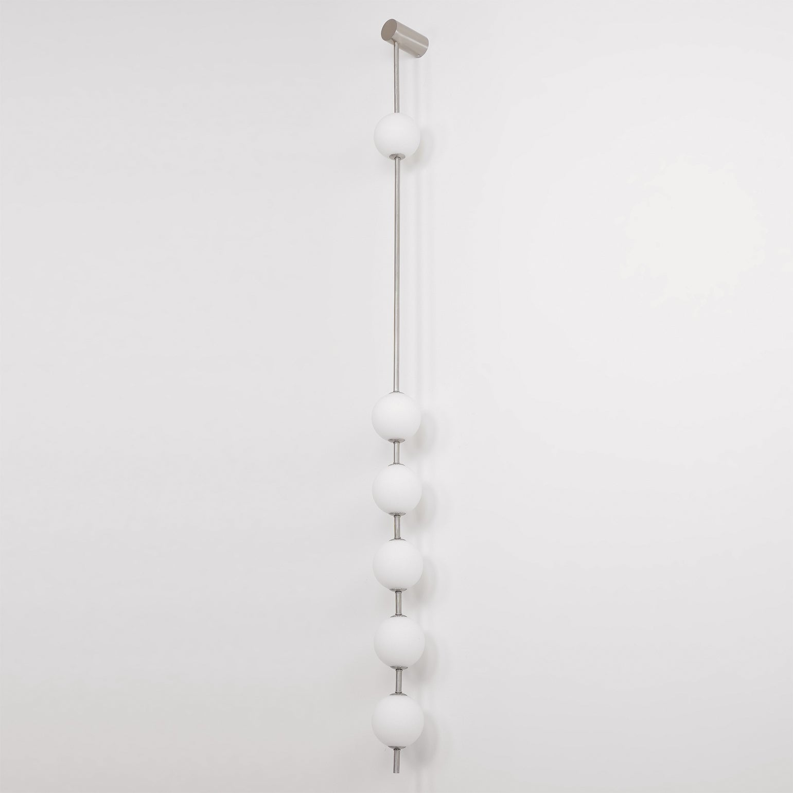 The Clérachic Stacked Globe Wall Sconce in brushed nickel, lit, six globes on a plain white backdrop.