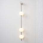 The Clérachic Stacked Globe Wall Sconce in brushed nickel, lit, three globes glowing against a plain wall.