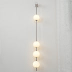 The Clérachic Stacked Globe Wall Sconce in brushed nickel, lit, four globes glowing beside a lace curtain.