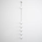 The Clérachic Stacked Globe Wall Sconce in brushed nickel, lit, four globes photographed near sheer lace.