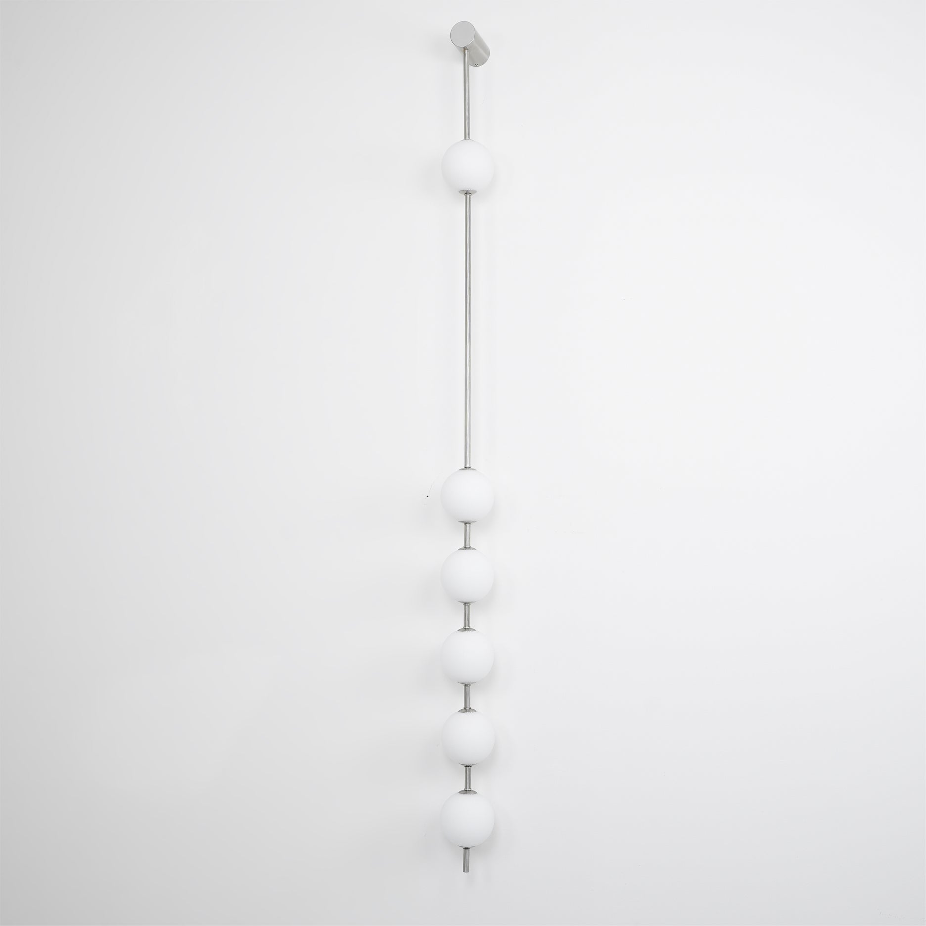 The Clérachic Stacked Globe Wall Sconce in brushed nickel, lit, four globes photographed near sheer lace.
