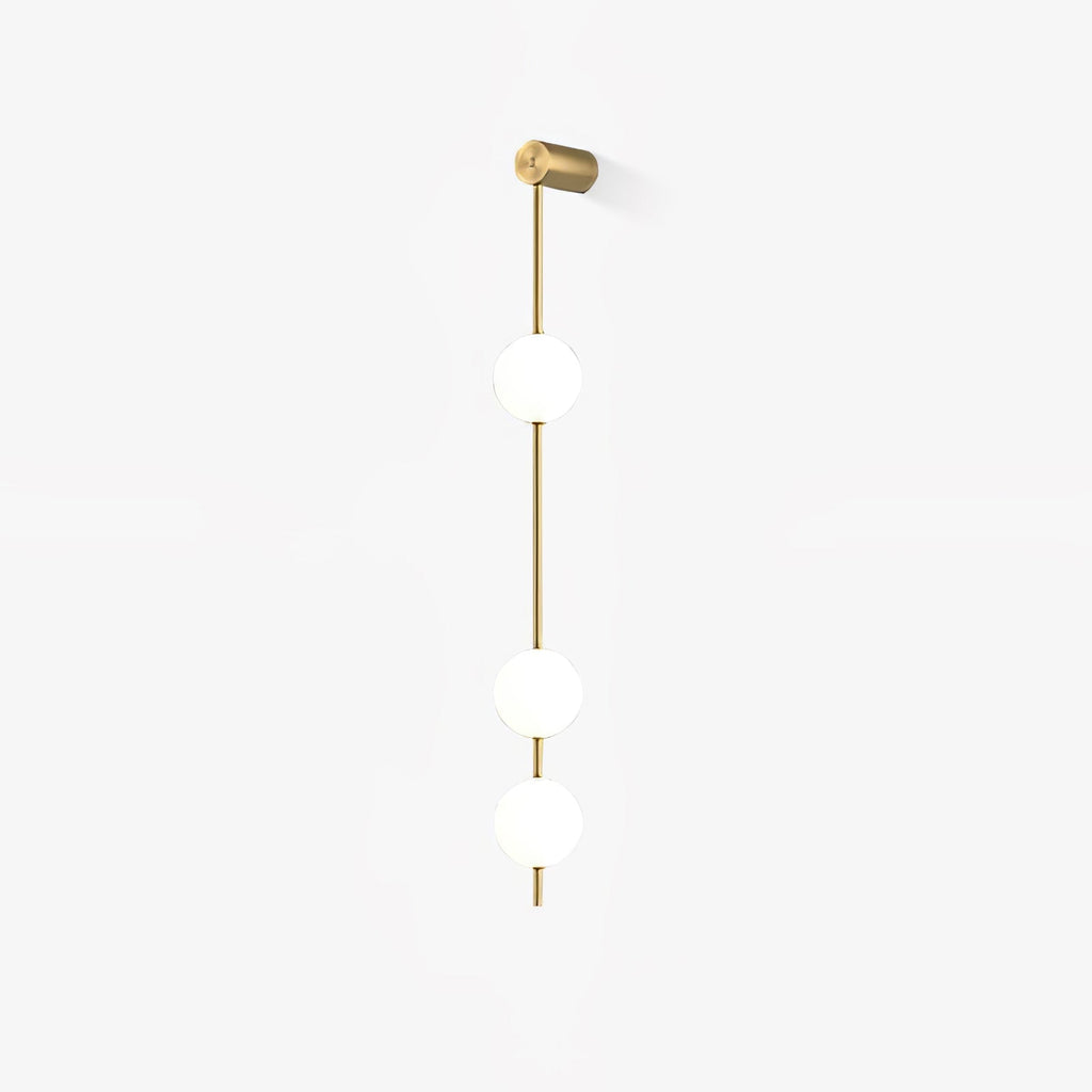The Clérachic Stacked Globe Wall Sconce in brass, lit, three globes glowing softly against a white backdrop.