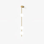 The Clérachic Stacked Globe Wall Sconce in brass, lit, three globes glowing softly against a white backdrop.