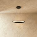 Clérachic's single-ring pendant hangs in matte black from three thin cables against a warm plaster wall.