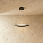 Clérachic's single-ring pendant hangs in matte black from three thin cables against a warm plaster wall.