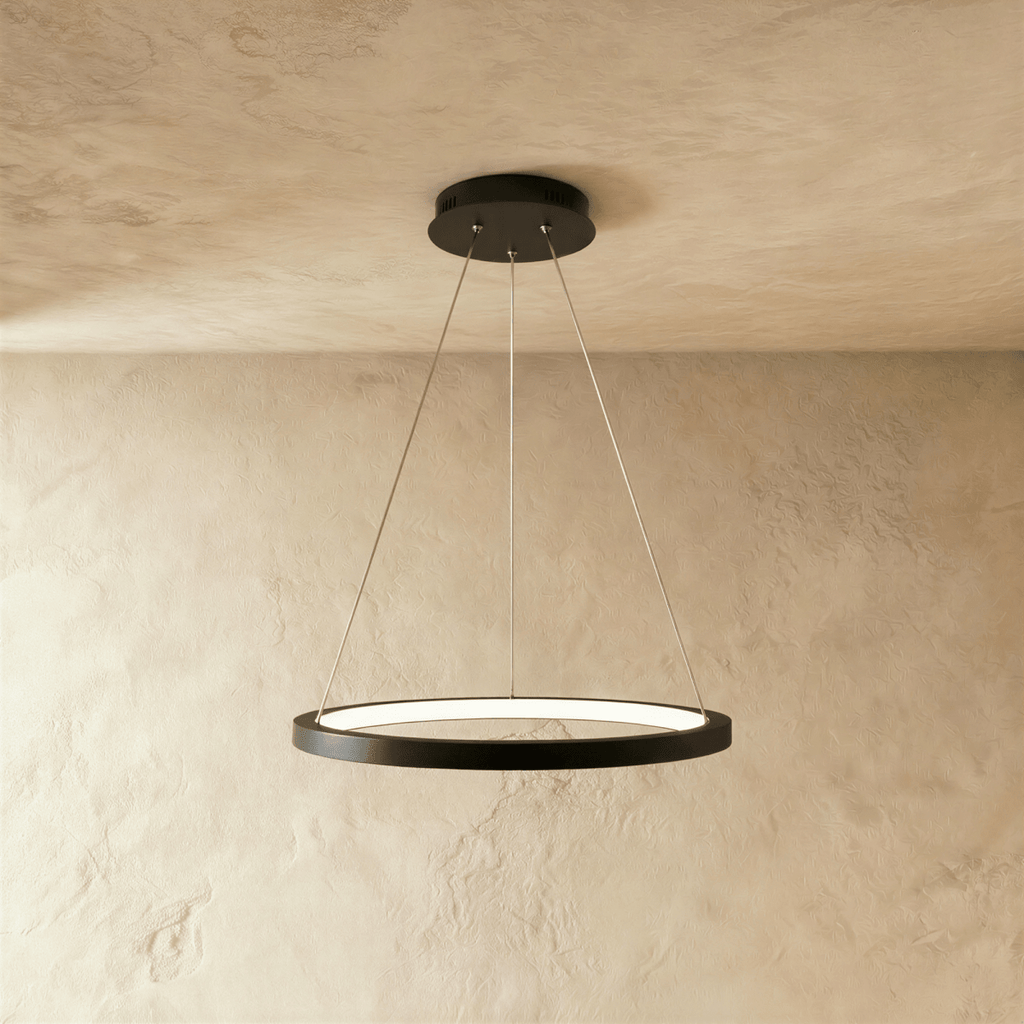 Clérachic's black ring pendant floats on slender cables, its LED edge glowing warm against a pale plaster wall.