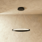 Clérachic's black ring pendant floats on slender cables, its LED edge glowing warm against a pale plaster wall.