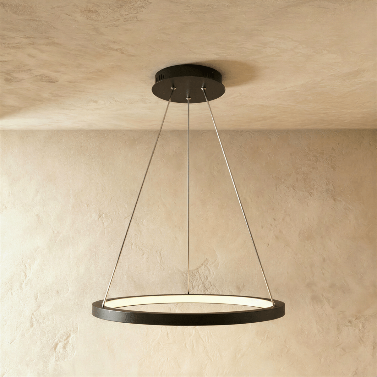 One black ring pendant from Clérachic hangs low on thin cables, framed by a soft sand-toned wall and ceiling.