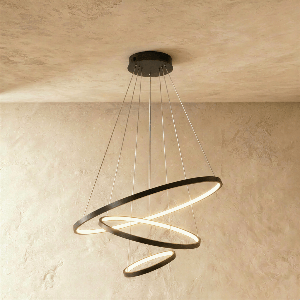 Clérachic's black four-ring chandelier cascades in a tightening spiral, the smallest ring glowing at its base.