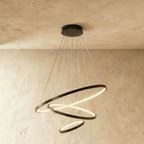 Clérachic's black four-ring chandelier cascades in a tightening spiral, the smallest ring glowing at its base.