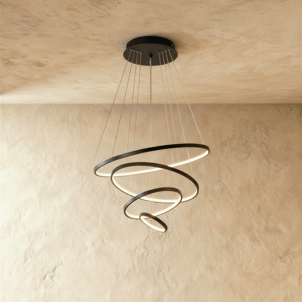Four black rings spiral downward in this Clérachic chandelier, each ring lit warm along its inner edge.
