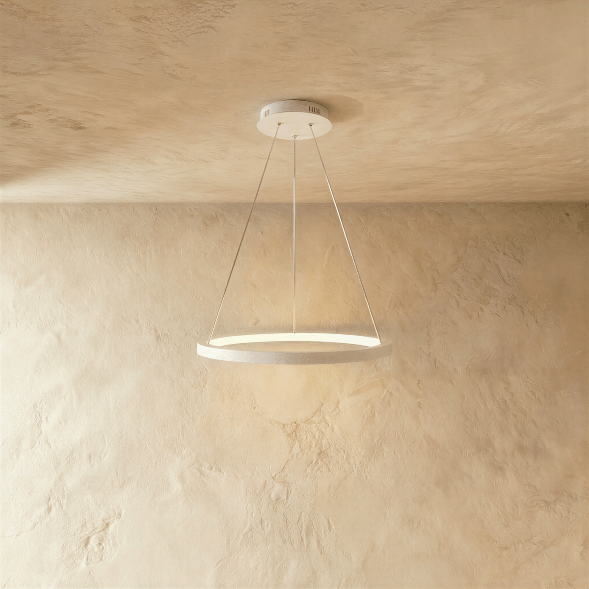 Clérachic's single-ring pendant in white hangs from three fine cables against a warm plaster wall.
