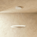 One white ring pendant from Clérachic hangs on thin cables, framed by a soft sand-toned wall and ceiling.