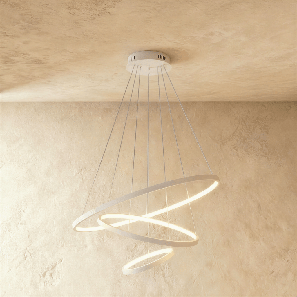 Clérachic's white three-ring chandelier spirals downward, the smallest ring glowing gently at its base.