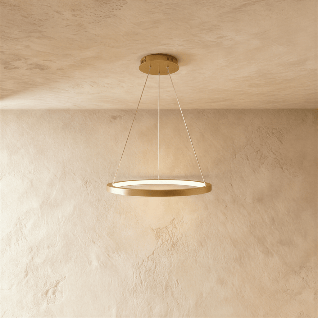Clérachic's single-ring pendant in a golden finish hangs from three fine cables against a plaster wall.
