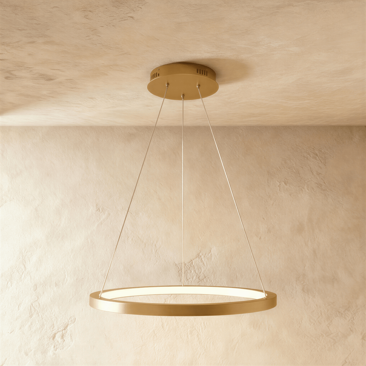One golden ring pendant from Clérachic hangs on thin cables, framed by a soft sand-toned wall and ceiling.
