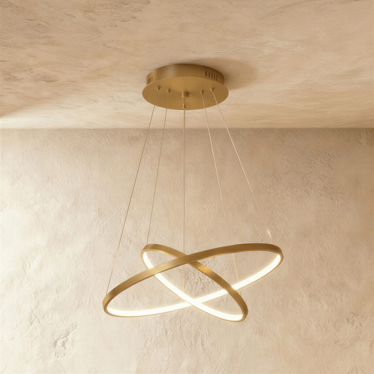 Clérachic's golden two-ring chandelier shows its rings overlapping in an X, lit warm above a textured room.