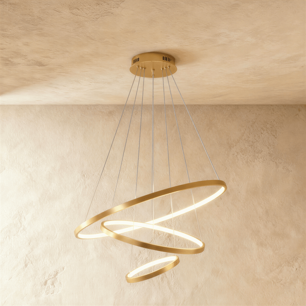 Clérachic's golden three-ring chandelier spirals downward, the smallest ring glowing gently at its base.