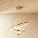 Clérachic's golden three-ring chandelier spirals downward, the smallest ring glowing gently at its base.