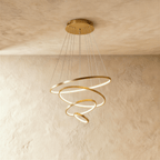 Four golden rings spiral downward in this Clérachic chandelier, each ring lit warm along its inner edge.
