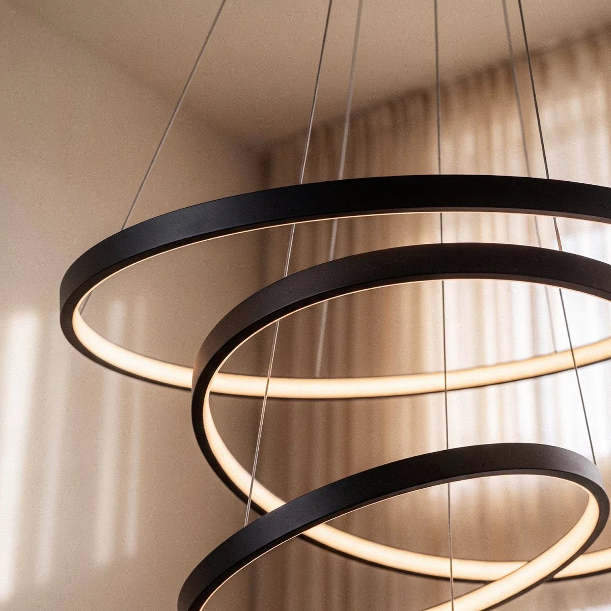 A close-up shows Clérachic's black rings cascading in a tight spiral, their LED edges glowing warm indoors.