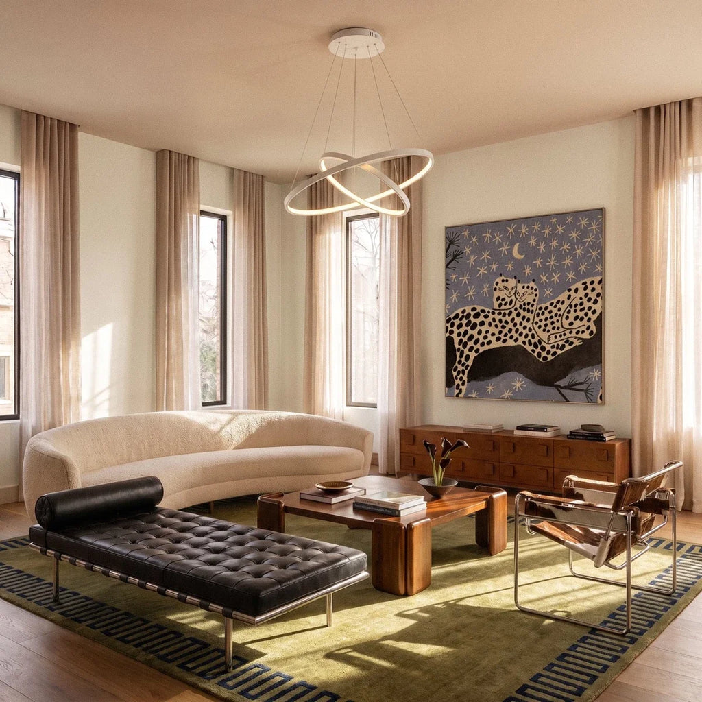 Clérachic's white two-ring pendant crosses above a curved sofa and patterned rug in a sunlit living room.