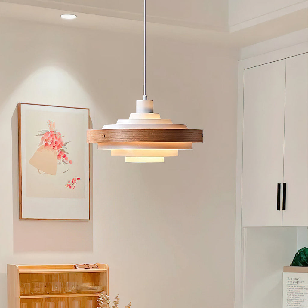 Clérachic stacked ring pendant seen in a bright kitchen, with a pink floral print and a wooden shelf of glasses behind.