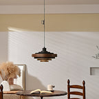 Black and walnut Clérachic pendant on a black cord, with dried pampas grass and a round wooden table in the room below.