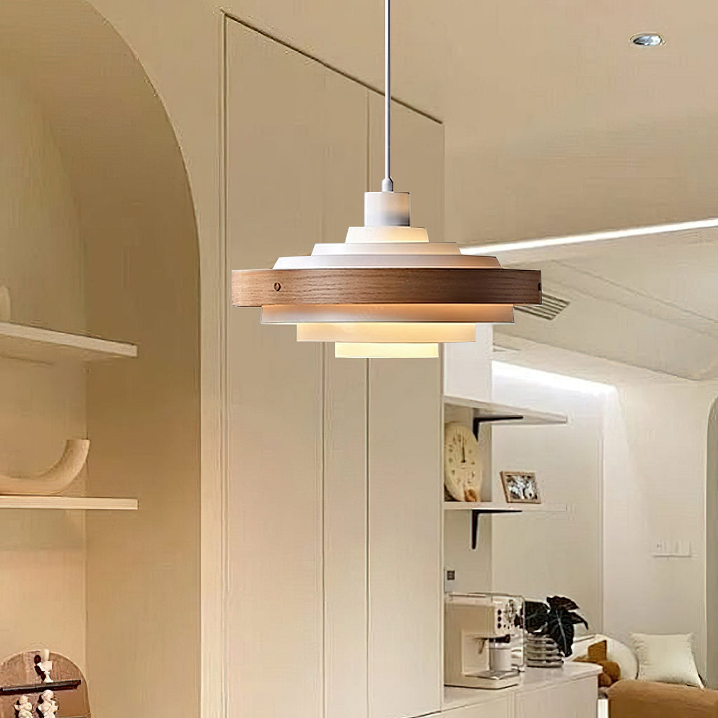 A Clérachic white and walnut pendant hangs under an arched ceiling, with an open kitchen and shelves in the background.