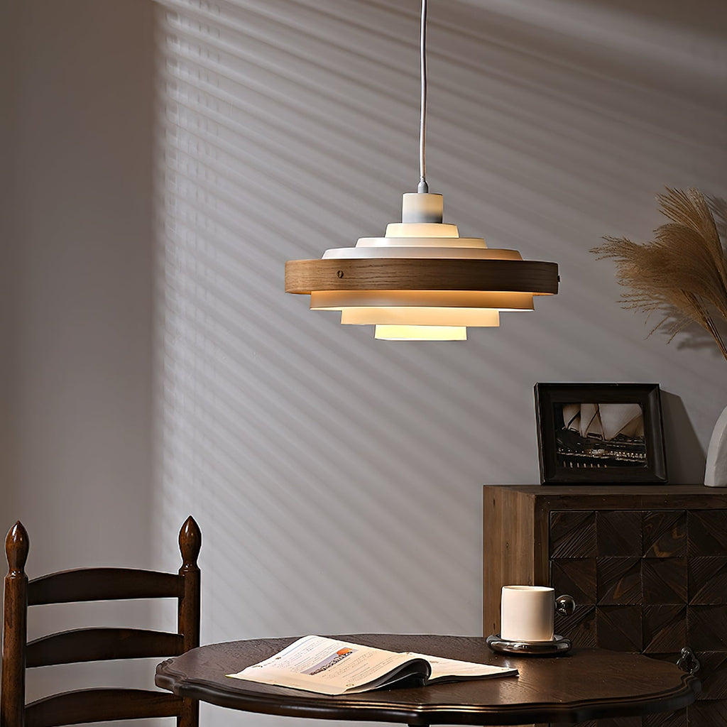 Clérachic stacked ring pendant seen a little farther back, above a dark wooden chair and a round table with a magazine.